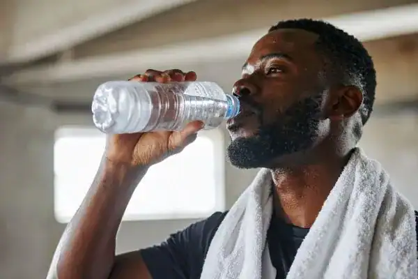 Hydration: The Secret Ingredient for a Toned Stomach and Enhanced Fitness 1 Image of man drinking water to improve hydration Deal after work out.